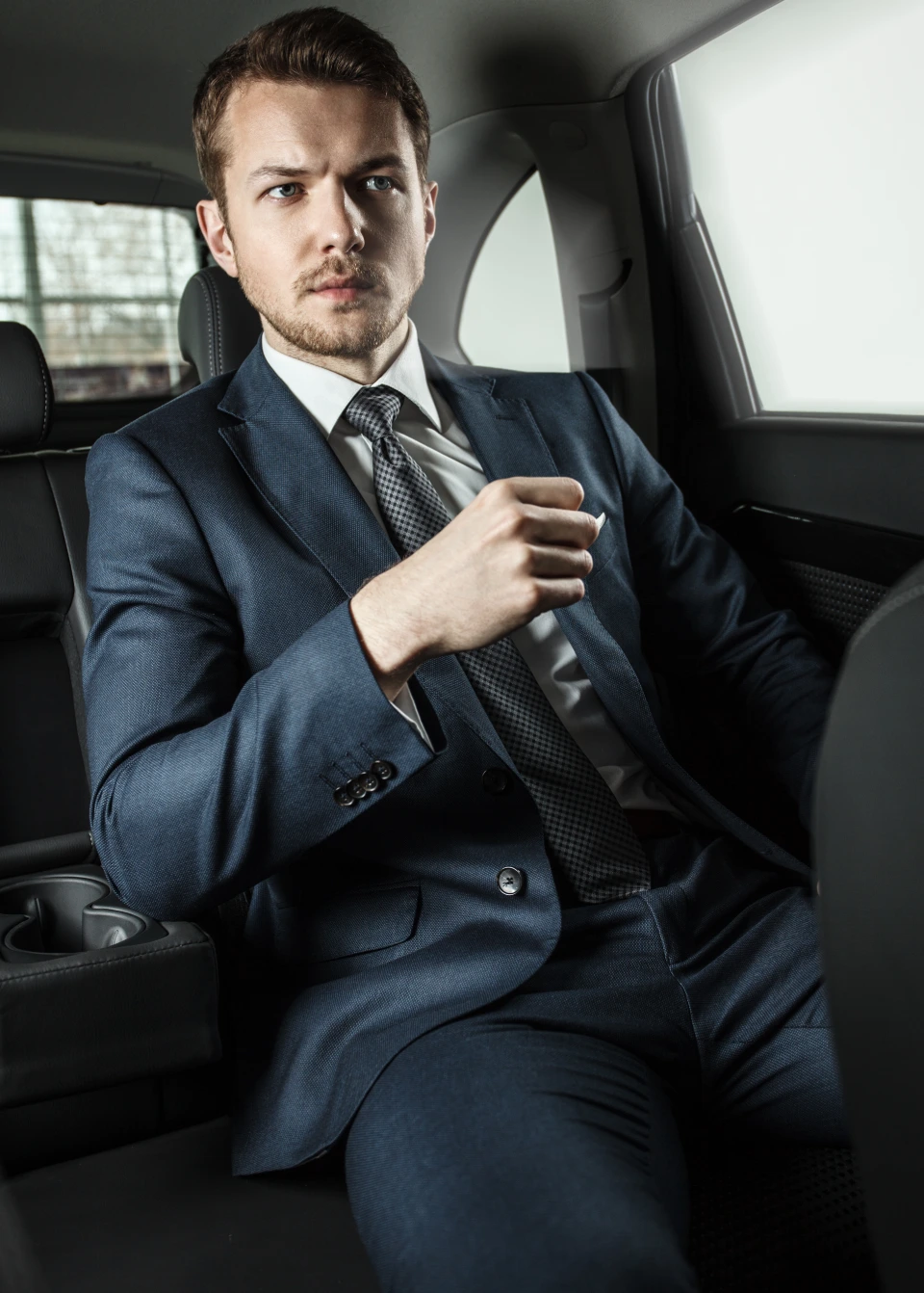 Chauffeur with luxury sedan at hotel entrance